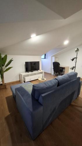 a living room with a blue couch and a tv at Apartamento T1 Arcos de Valdevez - centro da vila - 60 m2 total in Arcos de Valdevez