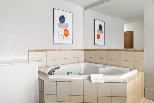 a bath tub in a bathroom with two pictures on the wall at Holiday Inn Express Lapeer by IHG in Lapeer