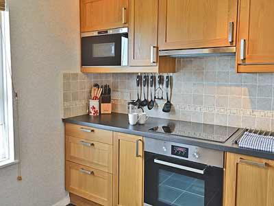a kitchen with wooden cabinets and a stove top oven at Sheerwater in Appledore