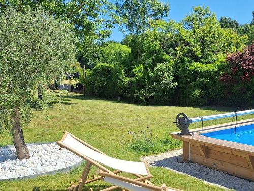 a wooden chair sitting next to a swimming pool at Longère cosy chic près de Bourges avec piscine, clim, WiFi et parking - FR-1-586-42 in Moulins-sur-Yèvre