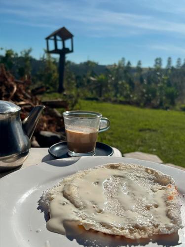 a plate of food on a table with a cup of coffee at Chalé Altos da Represa in Piedade