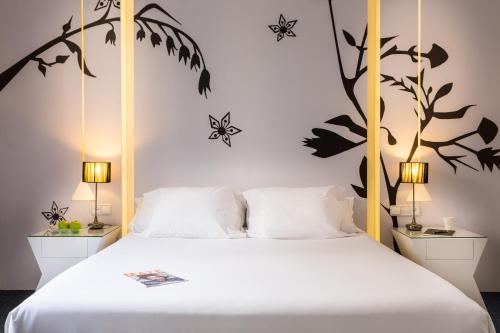 ein Schlafzimmer mit einem Bett mit weißer Bettwäsche und Pflanzen an der Wand in der Unterkunft Room Mate Mario, Madrid in Madrid
