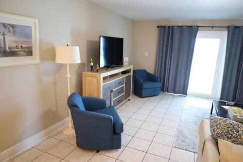 a living room with a blue chair and a tv at Mariner East in Panama City Beach