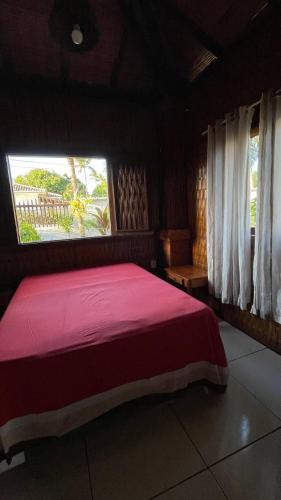 a bedroom with a large red bed with a window at Casa na orla in Porto Seguro