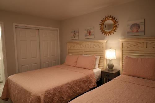 a bedroom with two beds and a mirror on the wall at Mariner East in Panama City Beach