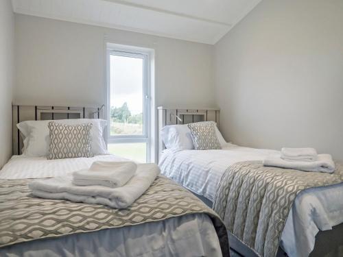 a bedroom with two beds with white sheets and a window at River Tees Lodge - Ukc4064 in Nunthorpe