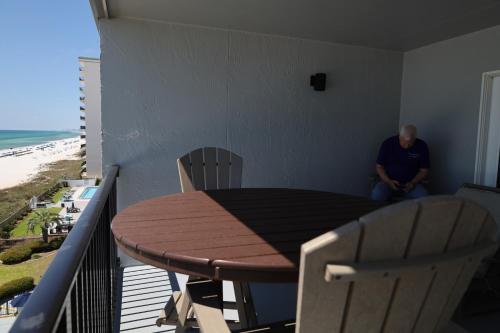 a man sitting on a balcony with a table and chairs at Mariner East in Panama City Beach