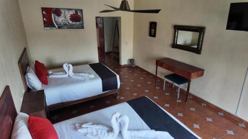 a bedroom with two beds and a desk and a mirror at Hotel Hacienda Tonalmain, Central Nueva in Guadalajara