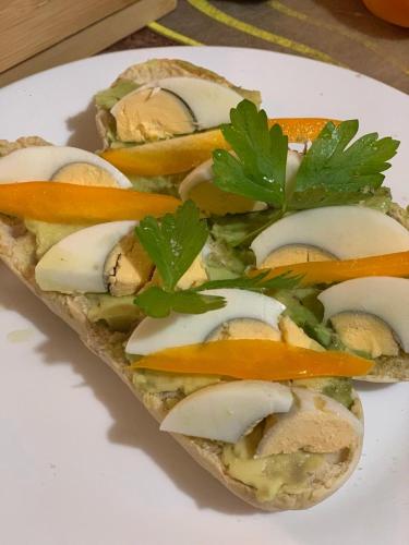 a sandwich with cheese and vegetables on a plate at Hotel Boutique CasAguacate close to Airport, Pedregal, Centro de Convenciones de Costa Rica in Potrerillos