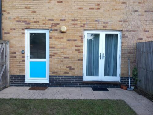 a brick house with white doors and a fence at Cosy 1-Bed Studio in Northolt perfect to unwind in Northolt