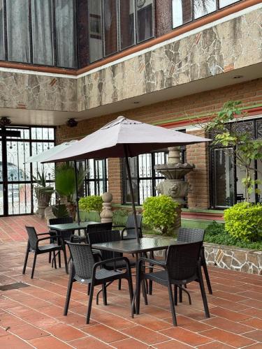 a patio with tables and chairs and an umbrella at Hotel Hacienda Tonalmain, Central Nueva in Guadalajara