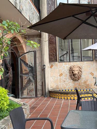a patio with a table and chairs and an umbrella at Hotel Hacienda Tonalmain, Central Nueva in Guadalajara