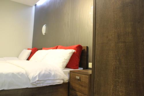 a bedroom with a bed with white sheets and red pillows at Studio rooms on the 2nd Floor in Yerevan