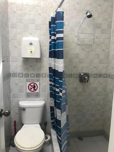a bathroom with a toilet and a shower curtain at Vacaciones Playa Club Casa Blanca Same Esmeraldas in Same
