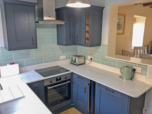 a kitchen with blue cabinets and a counter top at Felicity House in Staithes