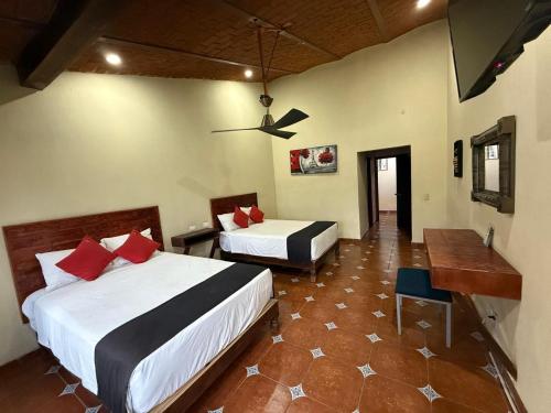 a hotel room with two beds and a desk at Hotel Hacienda Tonalmain, Central Nueva in Guadalajara
