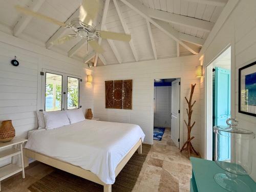 East EndにあるAmazing Views, Stunning Pool, Eco-Luxury Getaway - Dove Cottageの白いベッドと天井ファンのある寝室