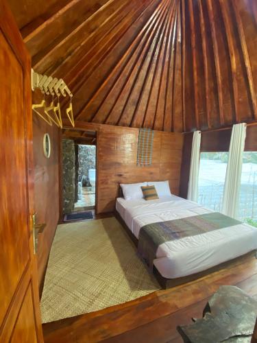 a bed in a room with a wooden ceiling at Alang Cottage in Masbagik