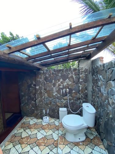 a bathroom with a toilet in a stone wall at Alang Cottage in Masbagik