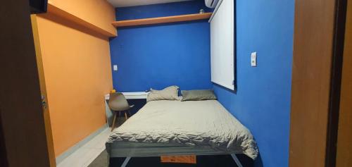 a blue room with a bed and a chair at Suíte AP belem in Belém