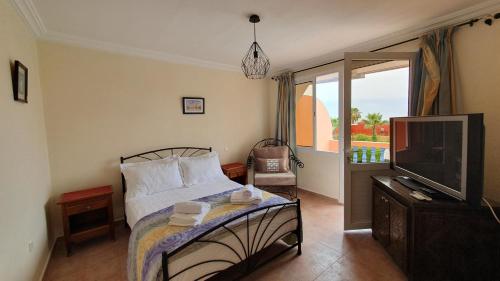 a bedroom with a bed and a tv and a balcony at L'oasis d'Agadir - Agadir's hidden Oasis in Agadir