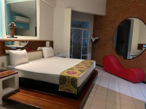 a bedroom with a bed with a mirror and a red chair at Cerezas in Cancún
