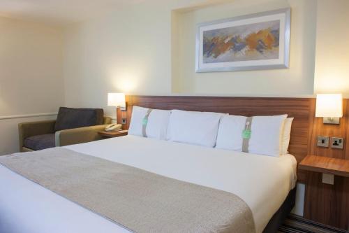 a hotel room with a large bed and a chair at Holiday Inn Leeds-Wakefield M1 Jct40 by IHG in Wakefield
