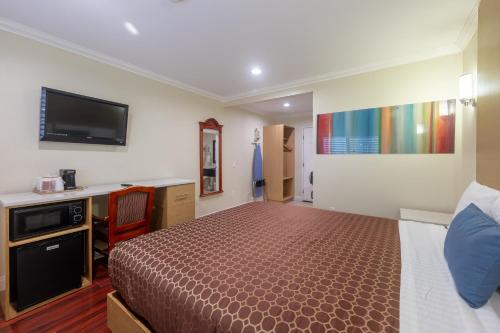 a bedroom with a bed and a desk and a tv at Hollywood City Inn in Los Angeles