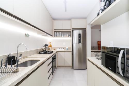 a kitchen with white cabinets and a stainless steel refrigerator at Apartamento Garden Caiobá com Piscina Praia Brava in Matinhos