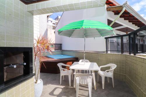 a patio with a table and chairs and an umbrella at Apartamento Garden Caiobá com Piscina Praia Brava in Matinhos