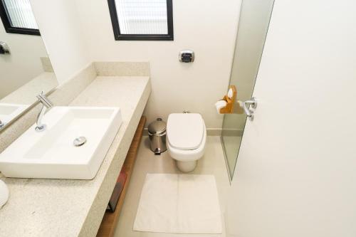 a bathroom with a white toilet and a sink at Apartamento Garden Caiobá com Piscina Praia Brava in Matinhos