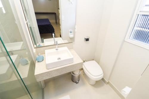 a white bathroom with a sink and a toilet at Apartamento Garden Caiobá com Piscina Praia Brava in Matinhos