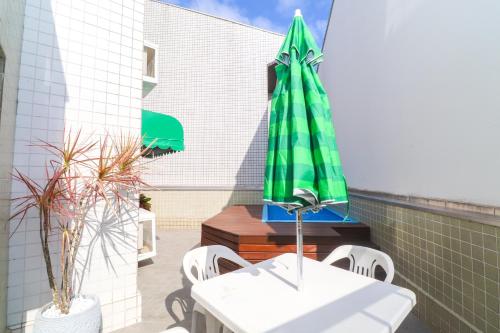 a patio with a table and a green umbrella at Apartamento Garden Caiobá com Piscina Praia Brava in Matinhos