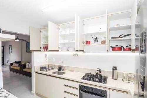 a kitchen with white cabinets and a sink at Apartamento Garden Caiobá com Piscina Praia Brava in Matinhos