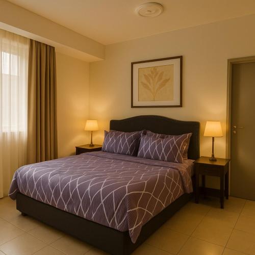 a bedroom with a bed with purple sheets and two lamps at Angsana Raintree Batu Caves with balcony 3Bedroom 2Bathroom in Batu Caves