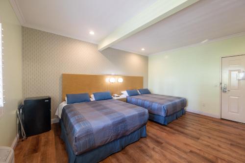 a hotel room with two beds and a television at Hollywood City Inn in Los Angeles