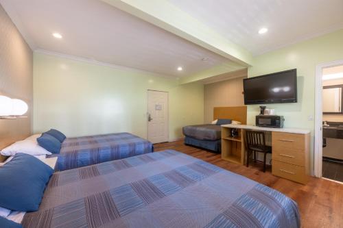 a hotel room with two beds and a flat screen tv at Hollywood City Inn in Los Angeles
