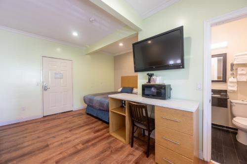 a hotel room with a desk with a tv on the wall at Hollywood City Inn in Los Angeles