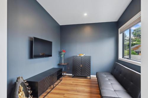 a living room with a couch and a flat screen tv at Seabreeze Retreat - Paraparaumu Holiday Home in Paraparaumu
