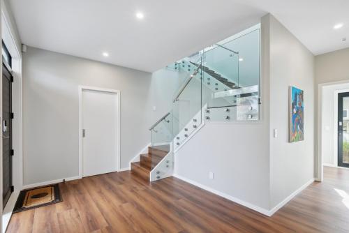 a white house with a glass stairwell at Seabreeze Retreat - Paraparaumu Holiday Home in Paraparaumu