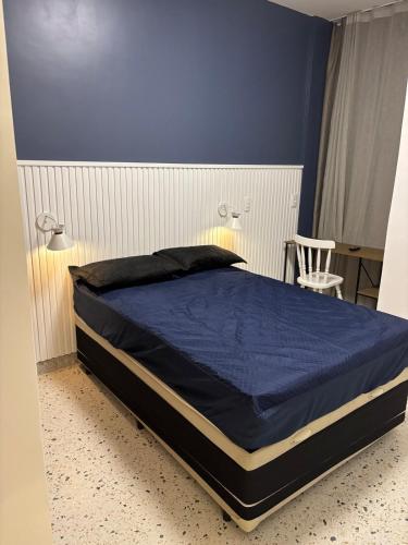 a bed in a bedroom with a blue wall at Flat Assinado e Sofisticado in Vitória