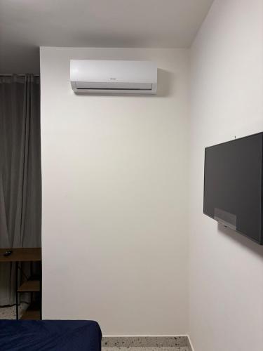 a room with a white wall with a tv on a wall at Flat Assinado e Sofisticado in Vitória