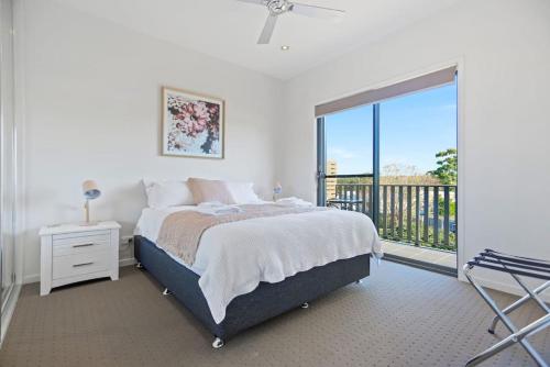 a white bedroom with a bed and a balcony at Aqua Shores 3 Bedroom - Newly renovated with Wifi, Linen, Netflix and AC in Huskisson
