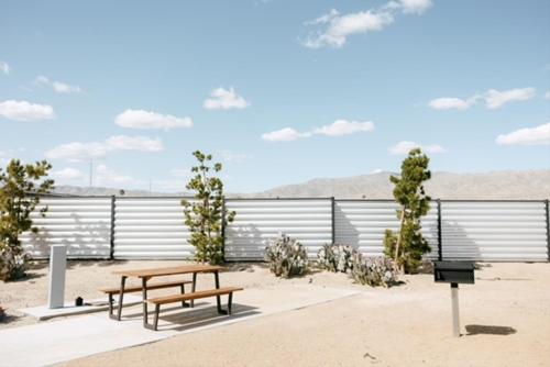 a picnic table and benches in front of a fence at Acres Landing in Desert Hot Springs