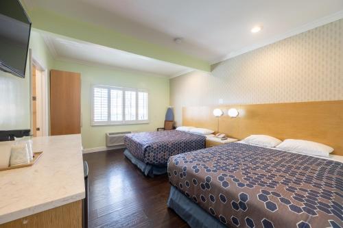 a hotel room with two beds and a flat screen tv at Hollywood City Inn in Los Angeles