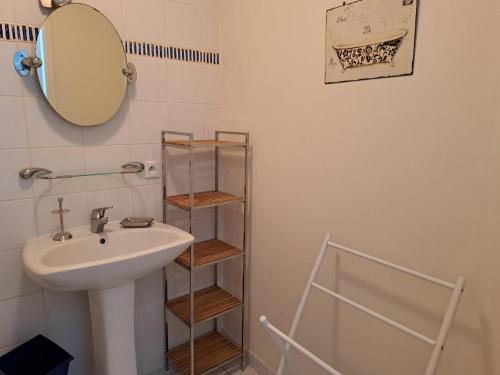 La salle de bains est pourvue d'un lavabo, d'un miroir et d'une étagère. dans l'établissement Maison confortable avec piscine privée, 3 chambres, proche forêt et plage. - FR-1-323-542, à Saint-Jean-de-Monts