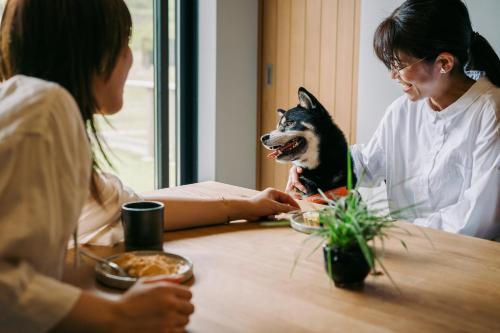 a woman sitting at a table with a dog at 山座熊川 Sanza-Kumagawa in Wakasa