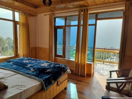 a bedroom with a bed and a balcony with windows at Prasama Homestay in Vashisht