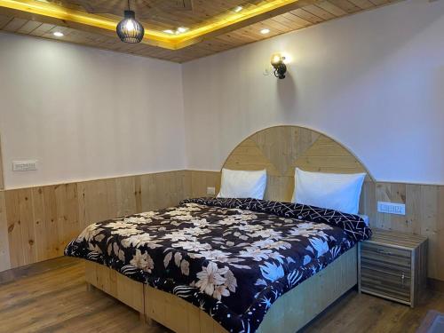a bedroom with a large bed with a wooden headboard at Prasama Homestay in Vashisht