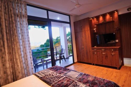 a bedroom with a bed and a balcony with a television at Hill Crest By Xaria Luxury Homes 2BHK Apartment in Dharampur